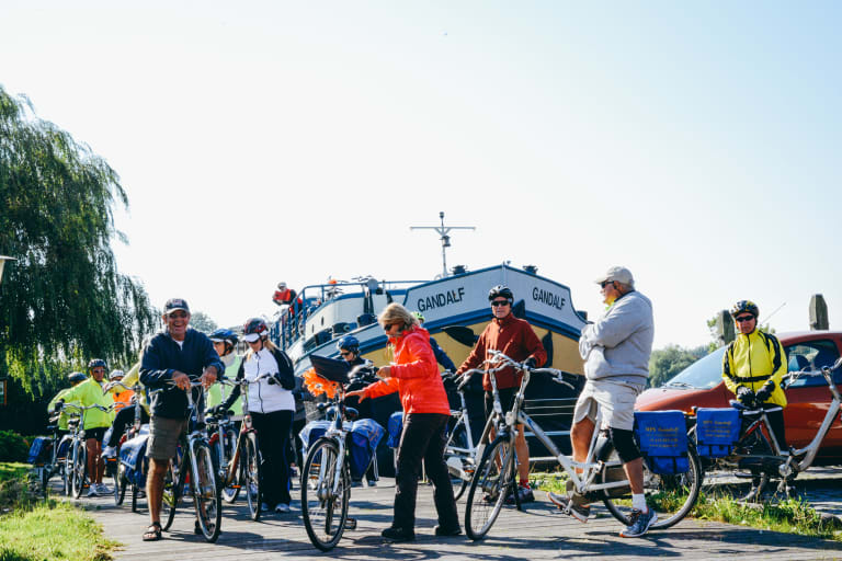 Gruppo di viaggiatori durante una vacanza bici e barca con Girolibero si preparano a partire, barca Gandalf sullo sfondo