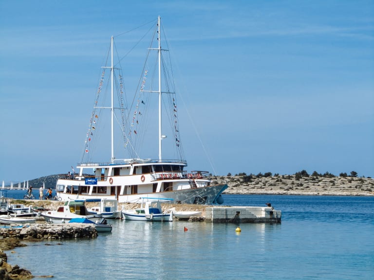 Barca con ponte in legno in navigazione lungo la costa croata.