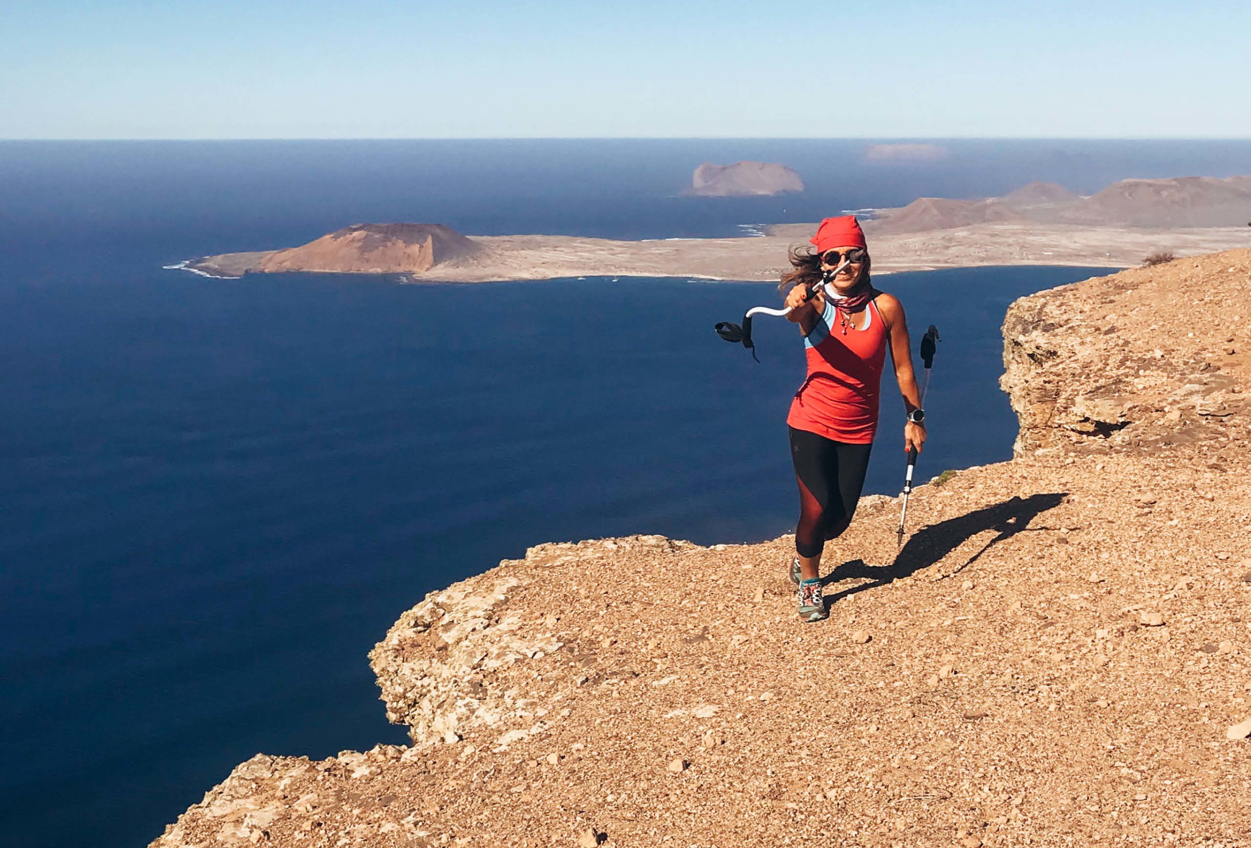 Escursionista in posa su una scogliera sassosa con vista sull'oceano Atlantico, trekking a Lanzarote