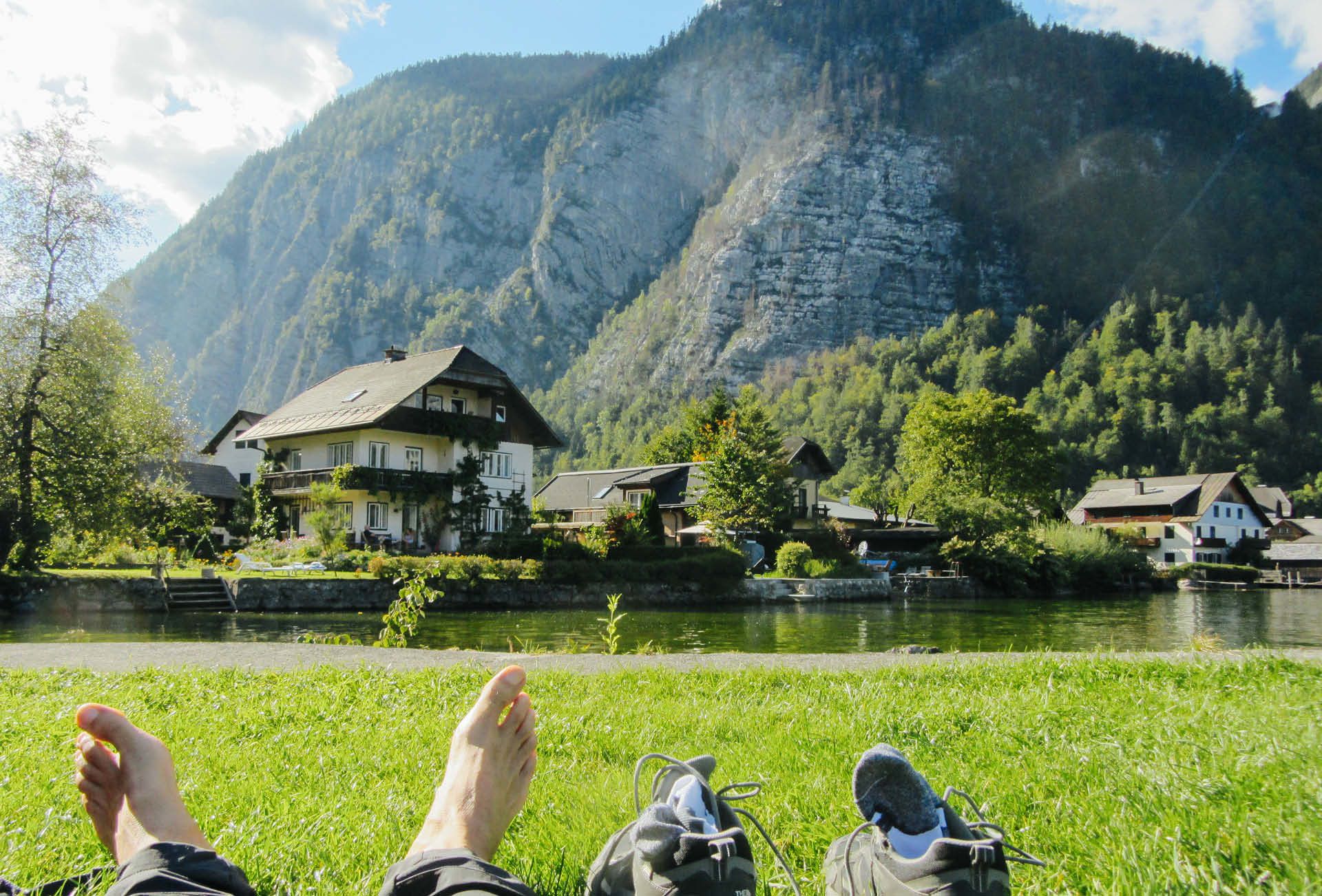 Persona sdraita su un prato ammirando il panorama alpino di Bad Goisern.