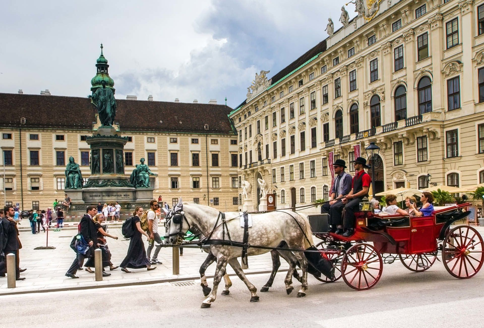 Ciclisti nel centro di Vienna vicino alla Hofburg con carrozza trainata da cavalli, Austria