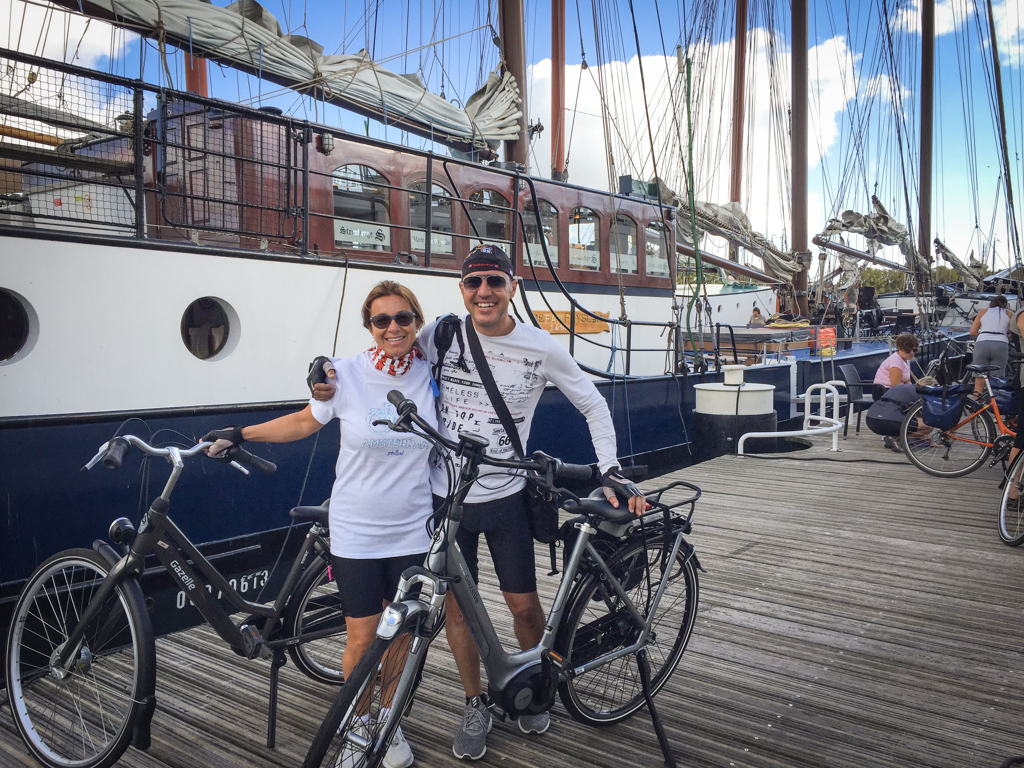 Paar Radfahrer vor einem Boot, das im Hafen der friesischen Inseln festgemacht hat, 