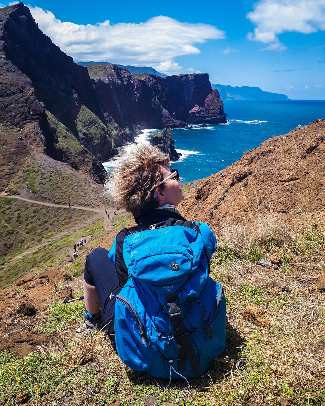 Escursionista seduta su una collina con vista sull'oceano, trekking a Madeira, Portogallo.