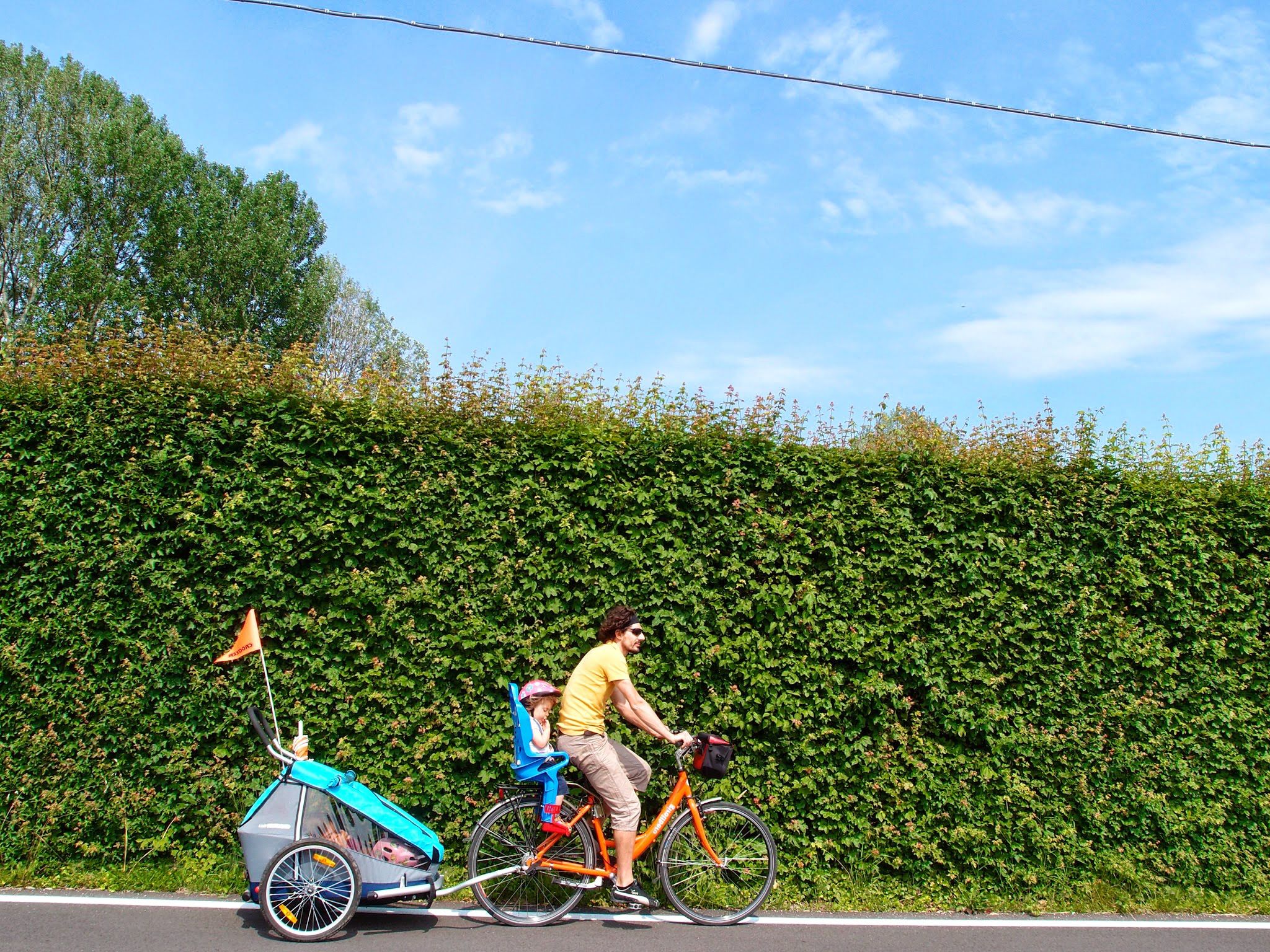 Radfahrer mit Kind im Fahrradwagen
