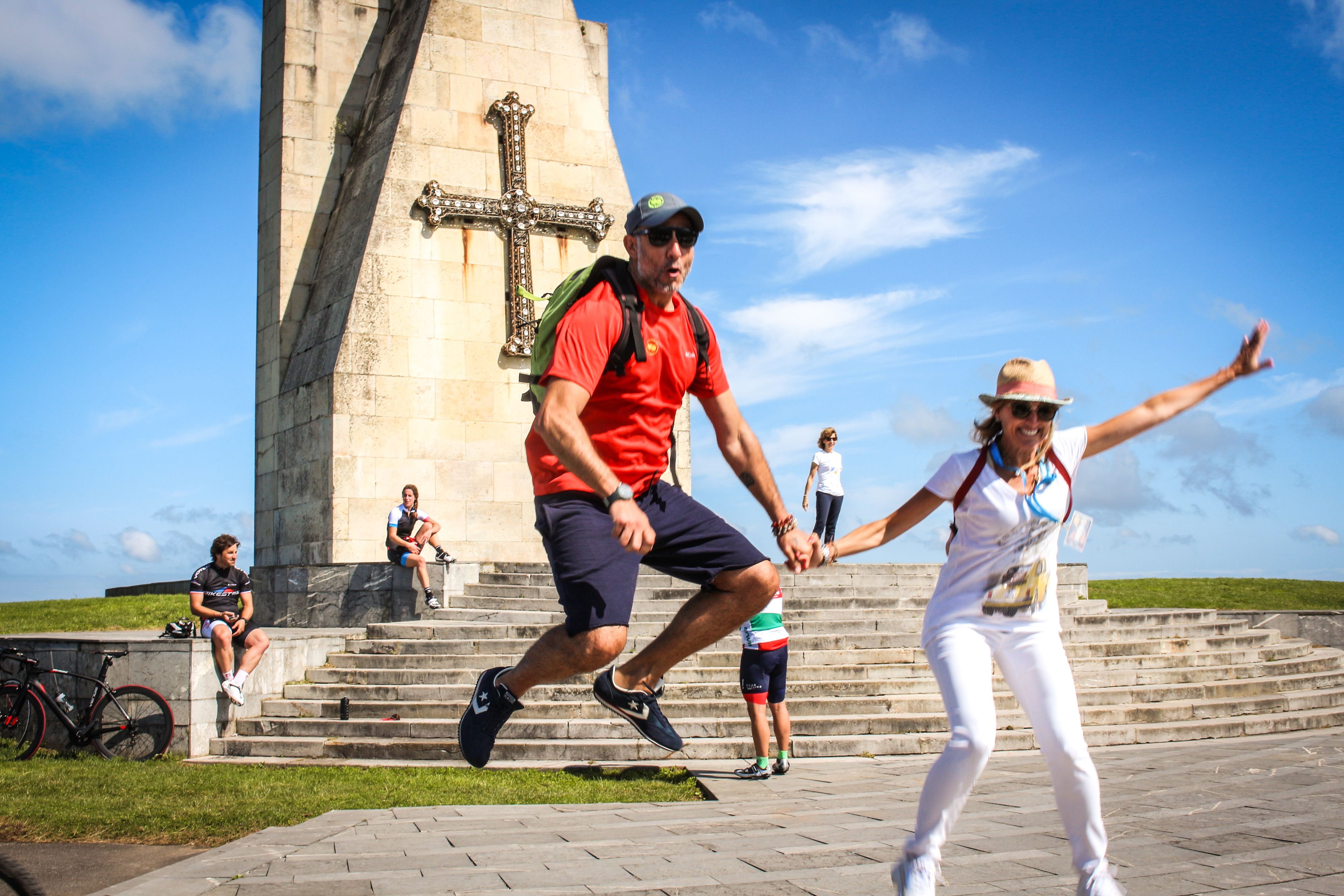 Pellegrini felici davanti a un monumento sull'oceano, viaggiare a piedi, camminare in Spagna, cammino sulla costa da Finisterre a Muxia, Galizia
