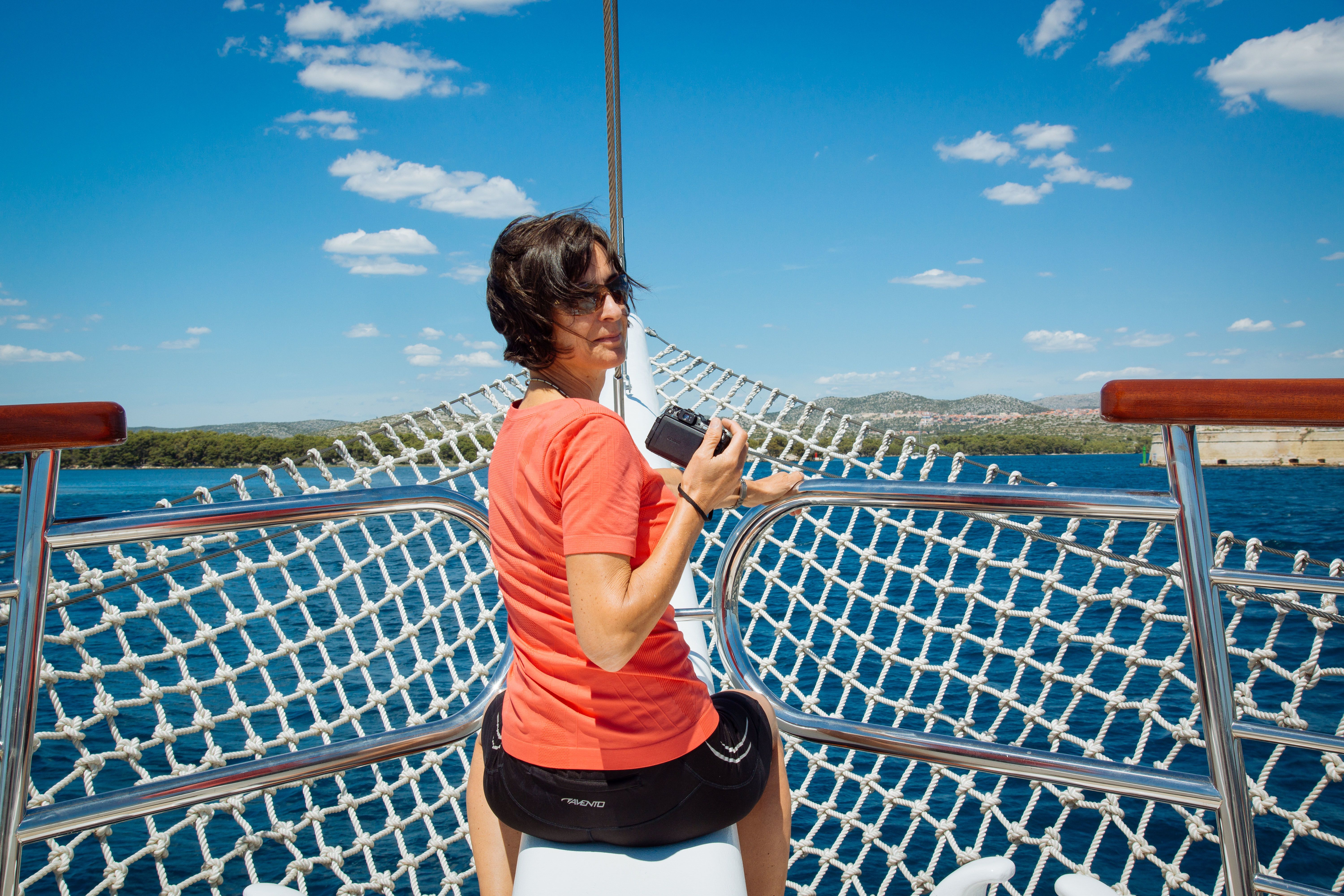 Frau mit Kamera auf dem Deck eines Bootes, Fahrrad- und Bootsurlaub 