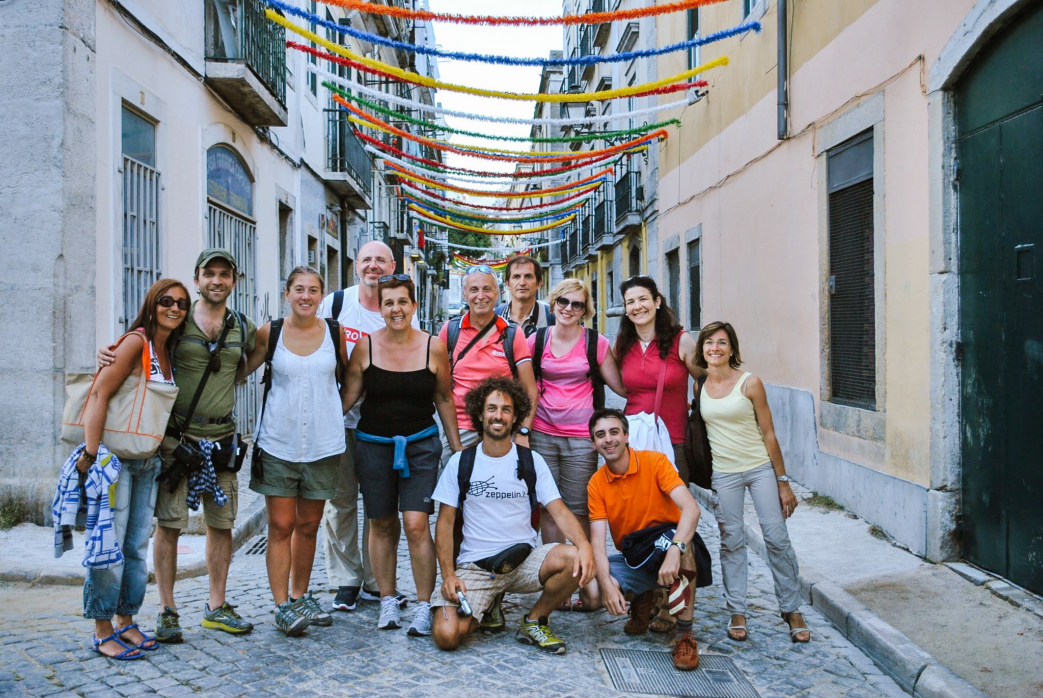 Foto di gruppo su una strada decorata con festoni colorati, Lisbona, Portogallo, gruppo in tour con Girolibero, da Porto a Lisbona, visite guidate, viaggi culturali