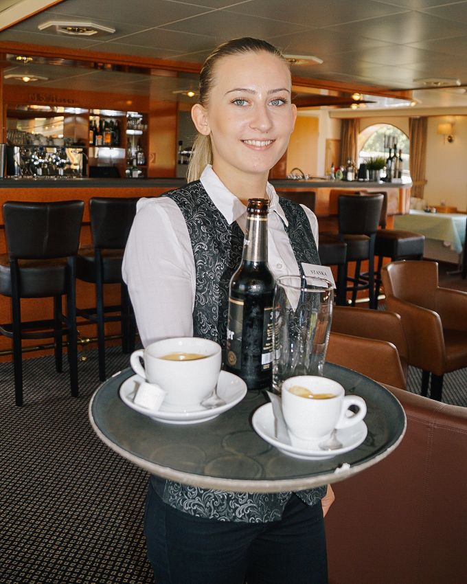 Cameriera che serve caffè e vino a bordo della barca Willemstad