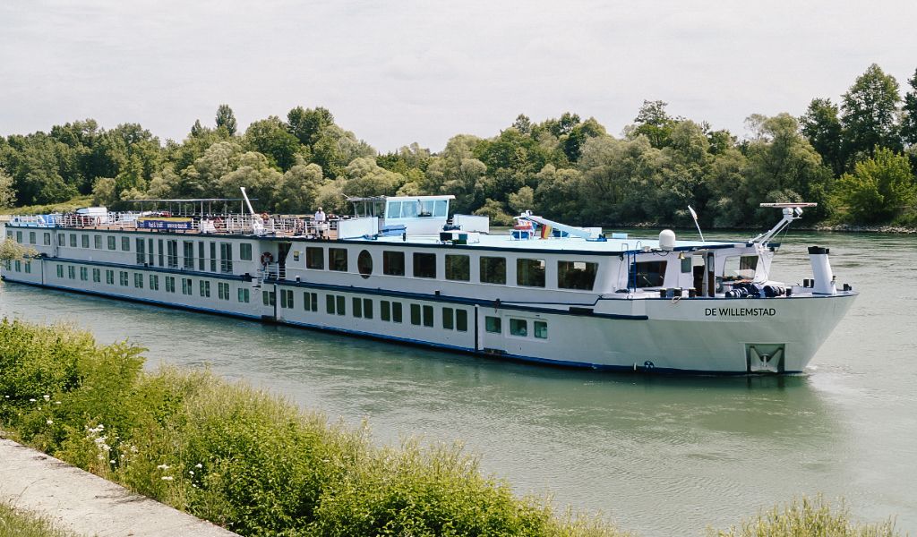 Nave da crociera in navigazione sul fiume con la campagna olandese sullo sfondo.
