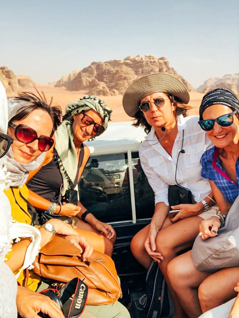 Amiche in vacanza nel deserto del Wadi Rum, Giordania, sedute su un fuoristrada con abbigliamento da escursione.