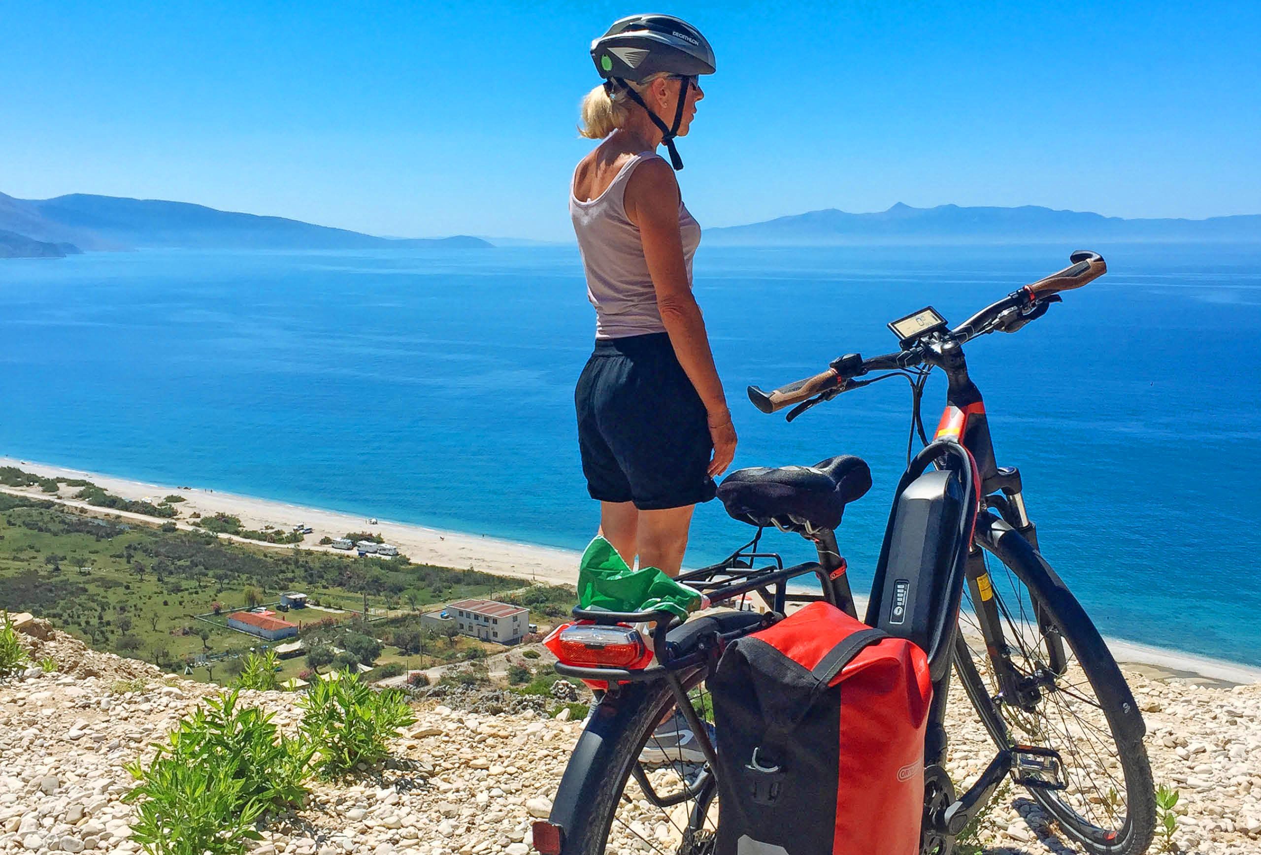 Ciclista girata di spalle ammira il mare dell'Albania