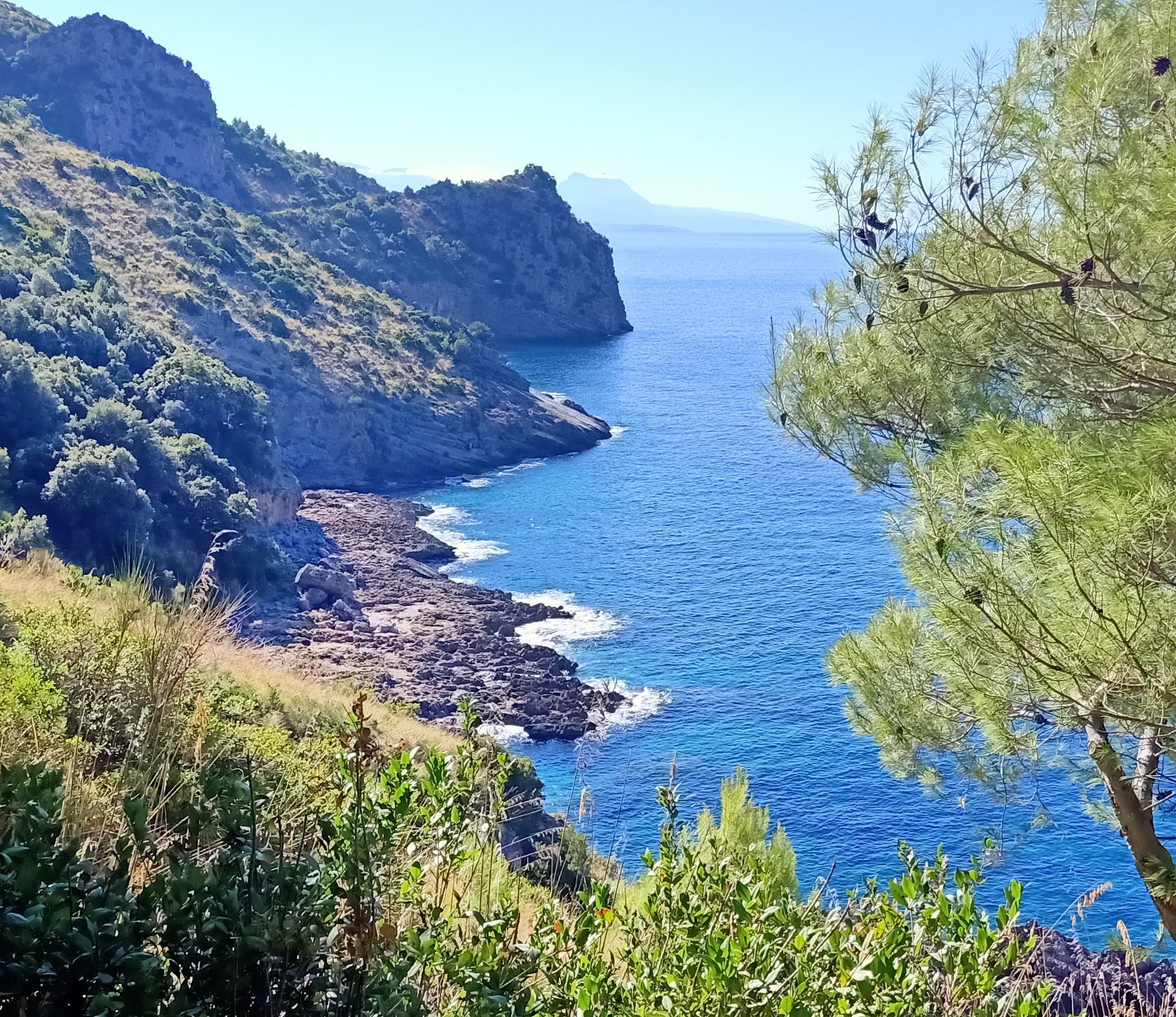 Vista panoramica su una baia rocciosa con acque turchesi lungo la costa del Cilento, Italia.