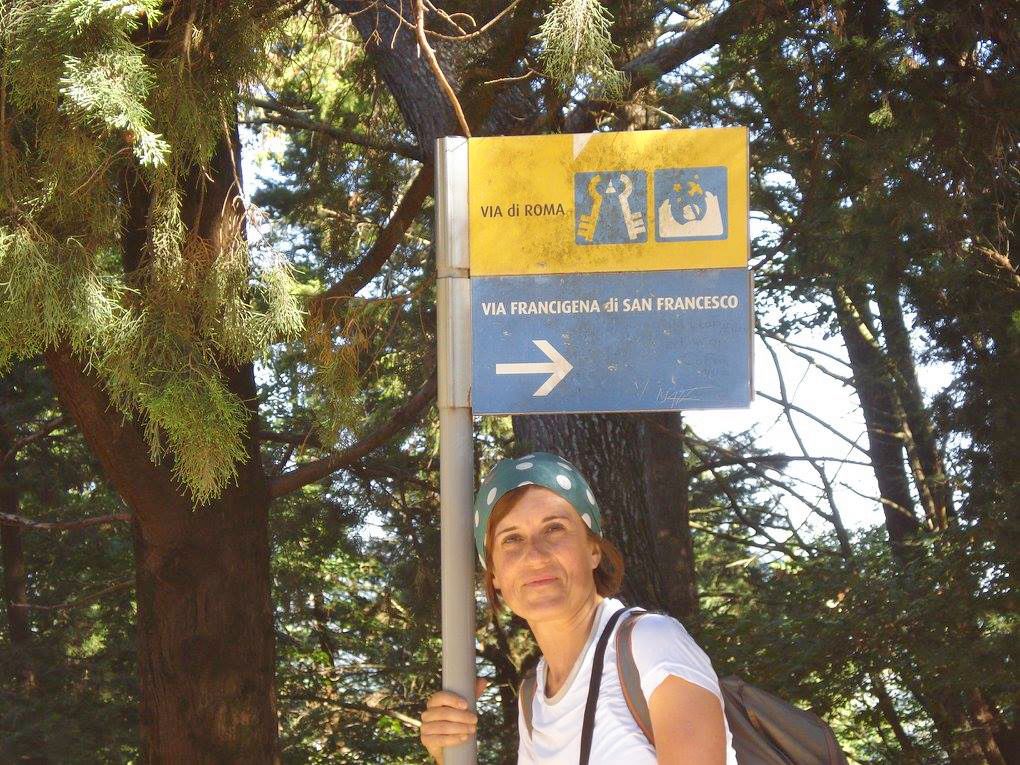 Escursionista sulla Via di Francesco con segnaletica, in mezzo alla natura.
