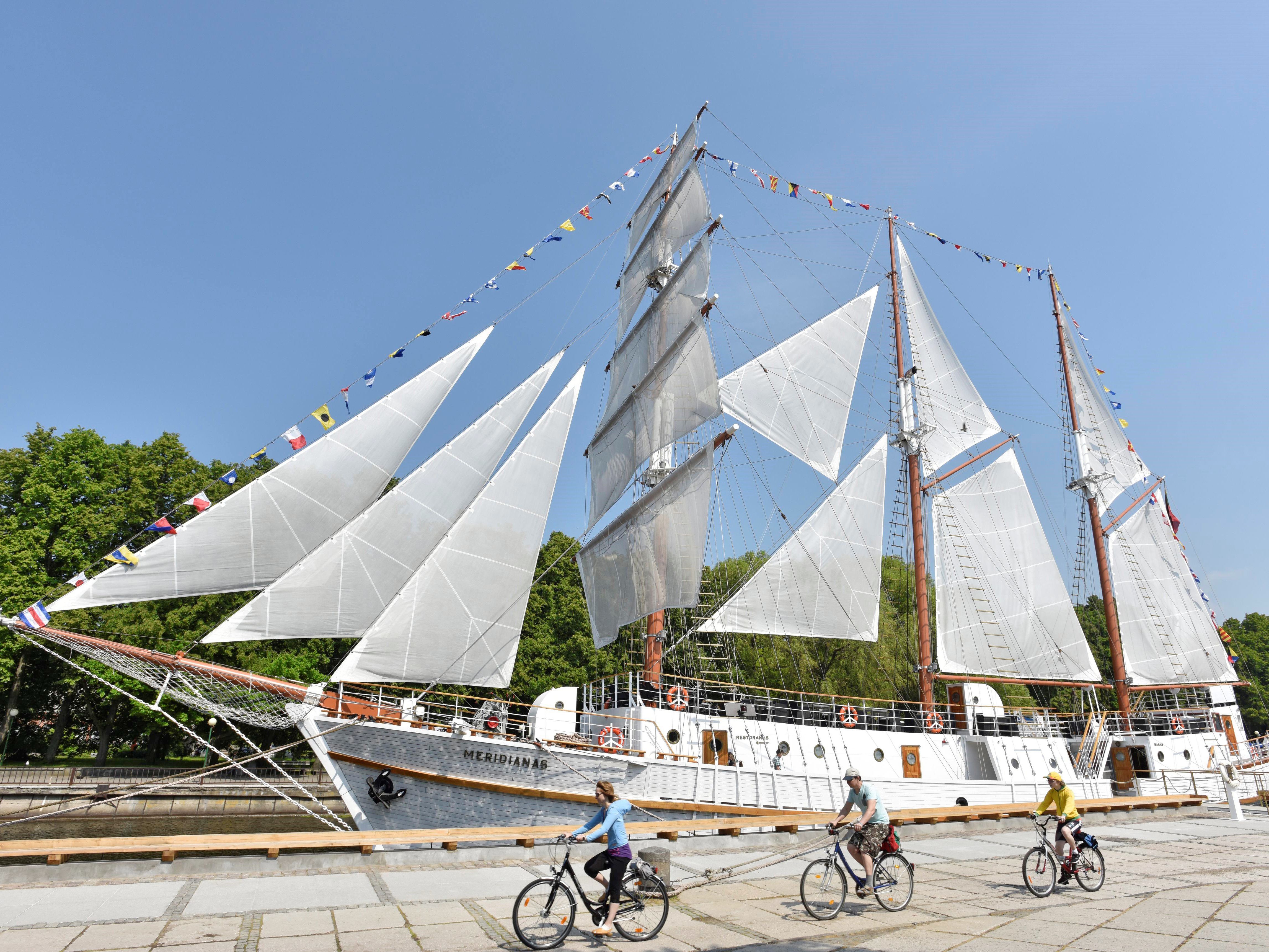 Barca a vela ormeggiata nella laguna, Penisola dei Curi, con biciclette parcheggiate sul pontile.