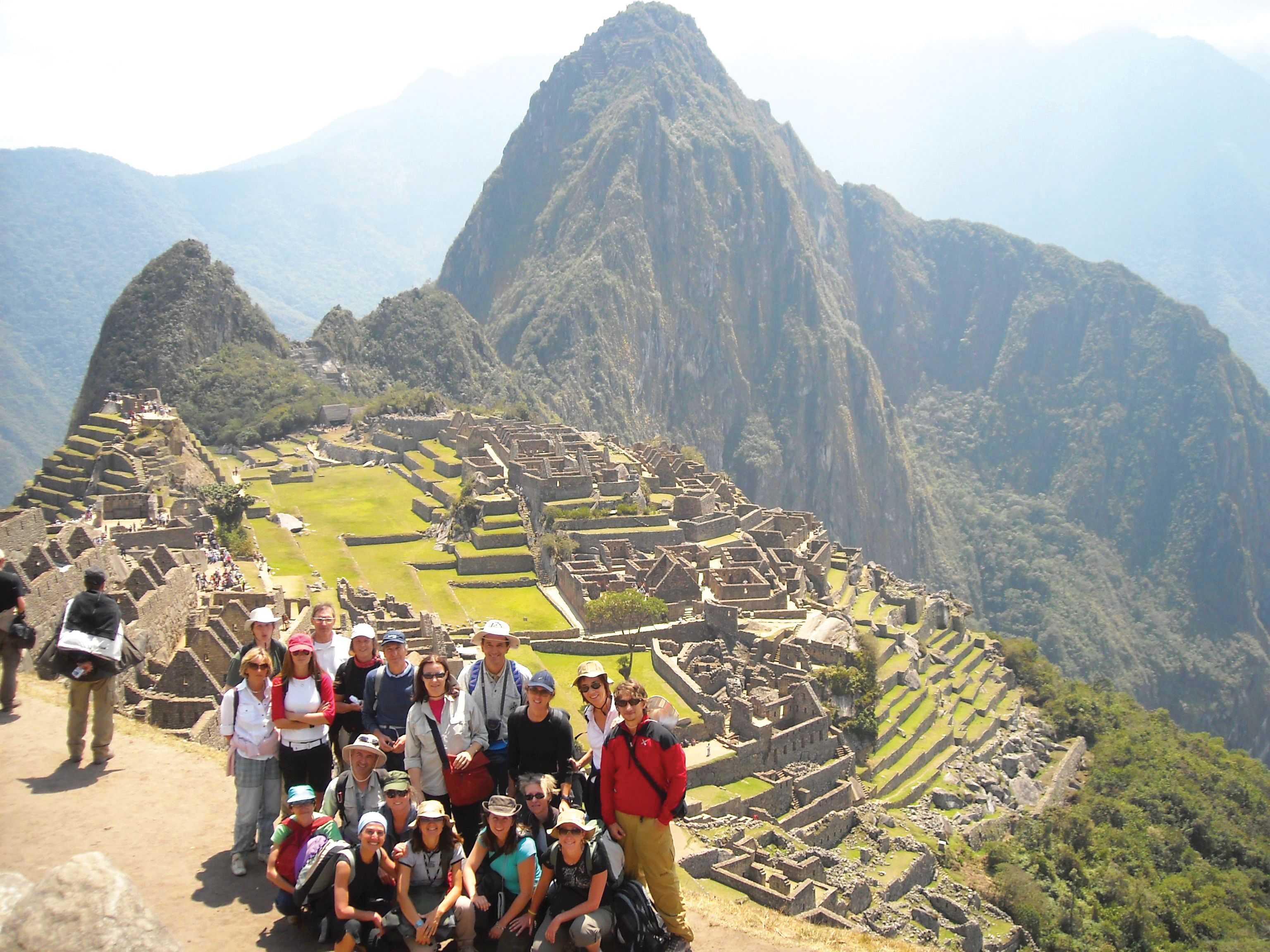 Gruppo di turisti a Machu Picchu con vista sulle antiche rovine Inca e montagne peruviane, tour 