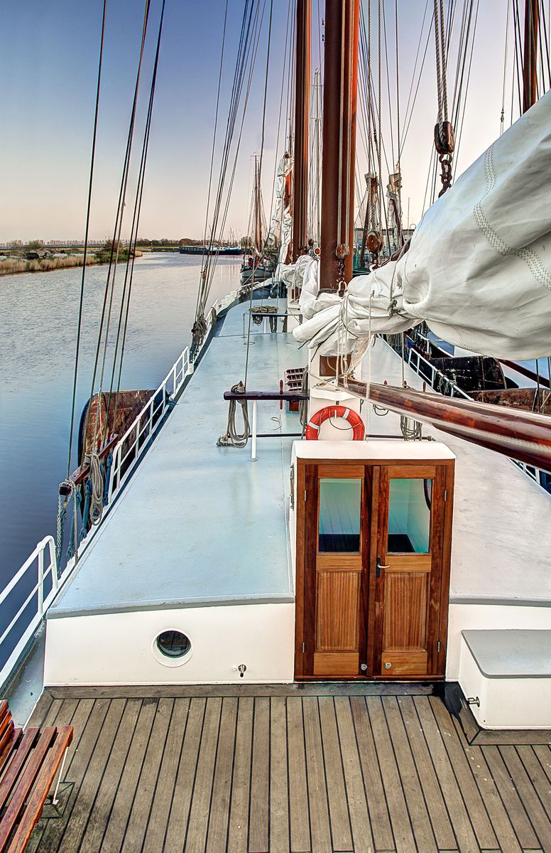 Nave a vela attraccata lungo un molo con vele bianche e cordame.