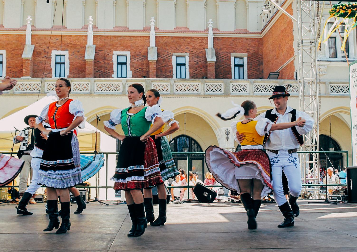 Ballerini in costume tradizionale durante un'esibizione folkloristica in una piazza della Polonia.