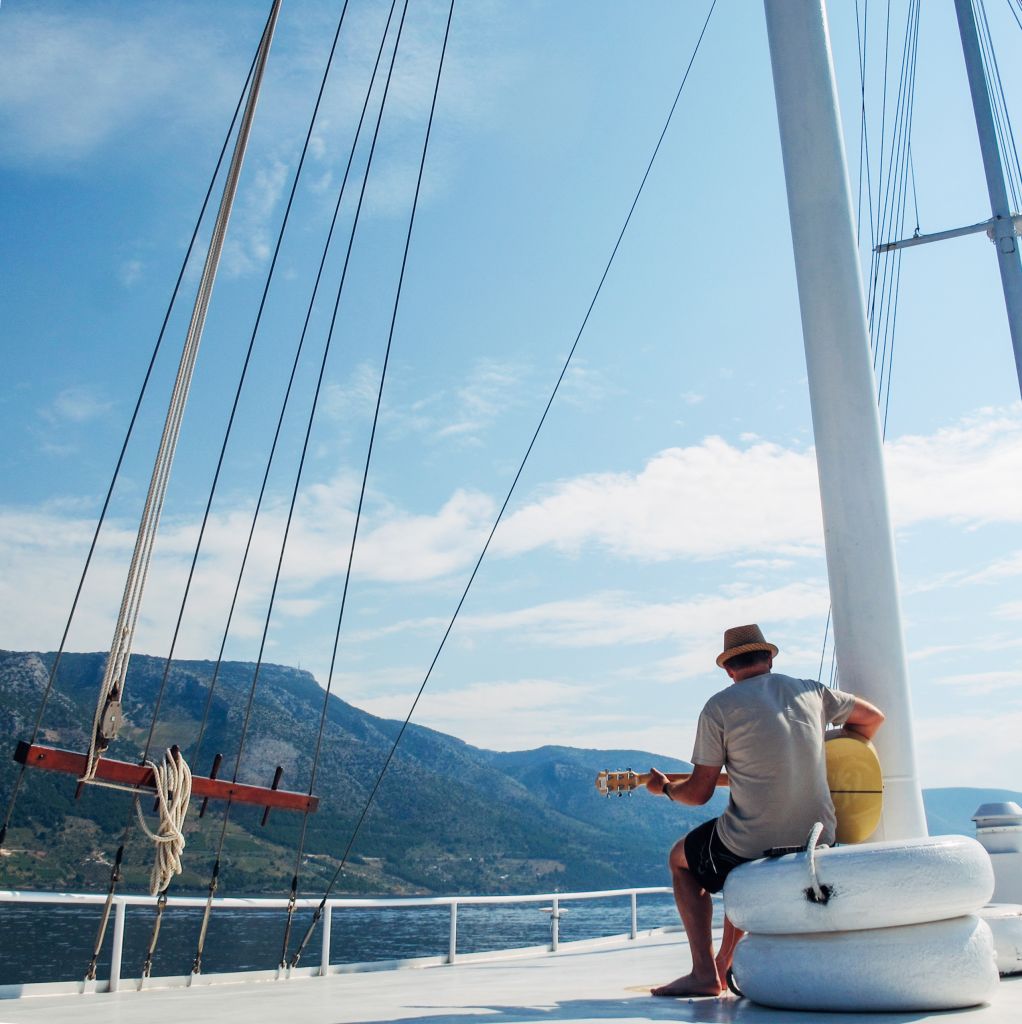 Person playing guitar on a sailboat, traveling by boat in Croatia