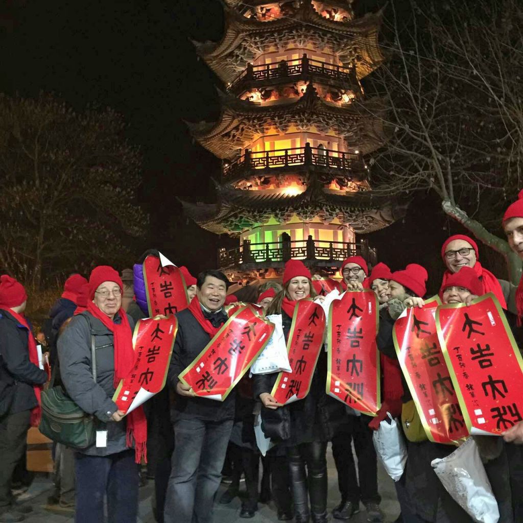 Gruppo di viaggiatori davanti a una pagoda illuminata nel centro storico di Shanghai durante un tour serale in Cina