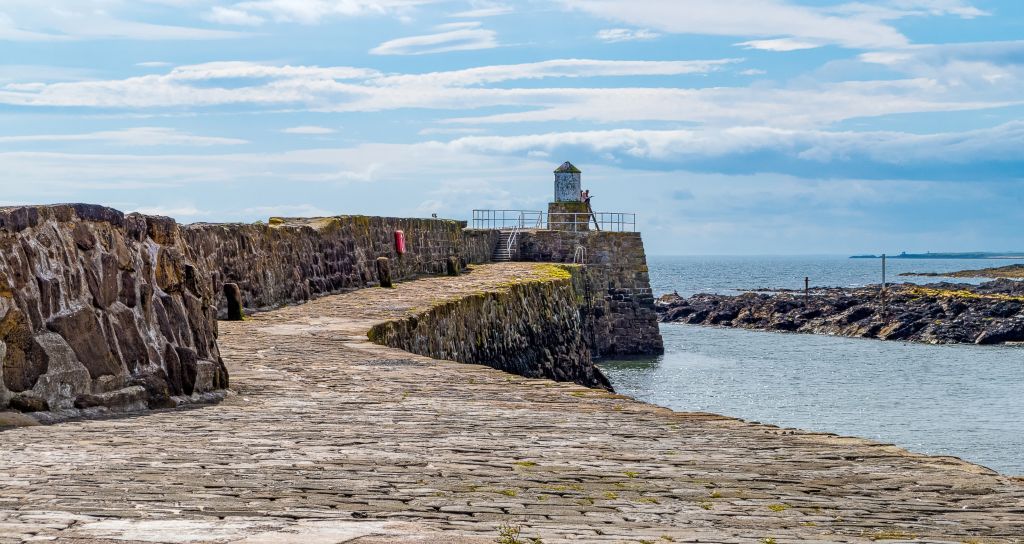 Diga in pietra che porta ad un faro lungo la costa
