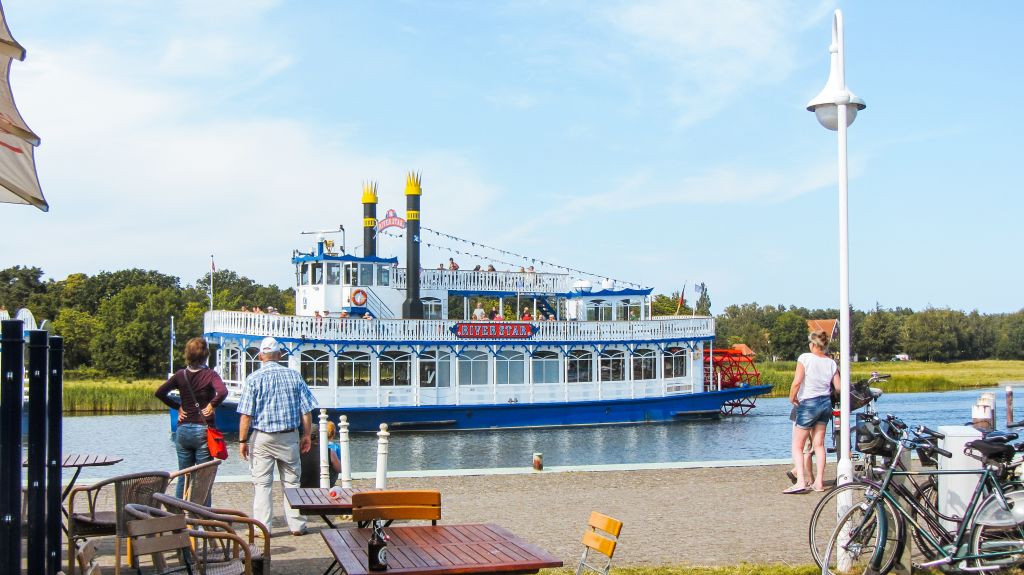 Piccolo molo con ciclisti e bici parcheggiate con battello sullo sfondo