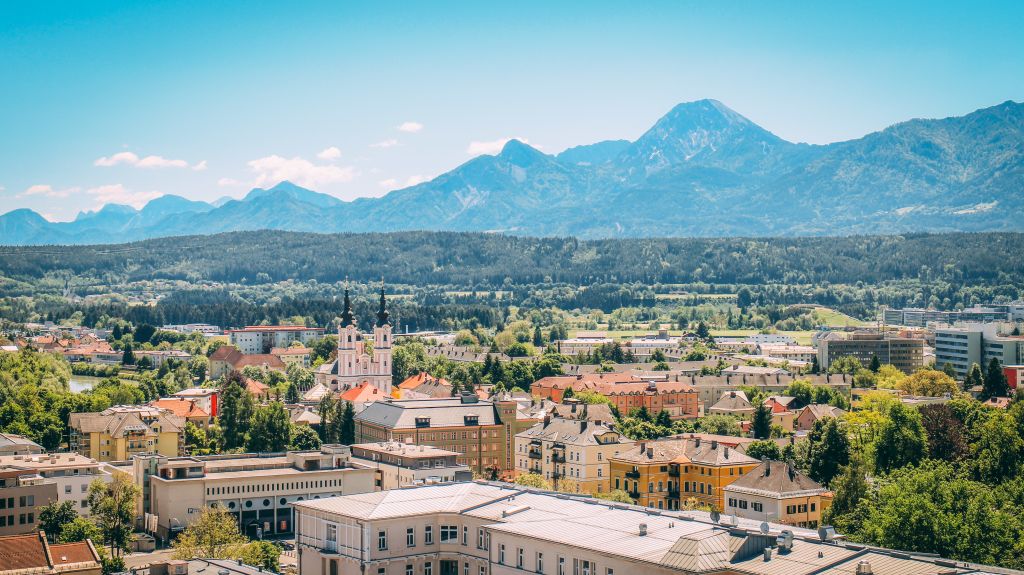 Visuale panoramica della città di Villach, alberi tra gli edifici, paesaggio alpino, vacanza in bici lungo l'Alpe Adria