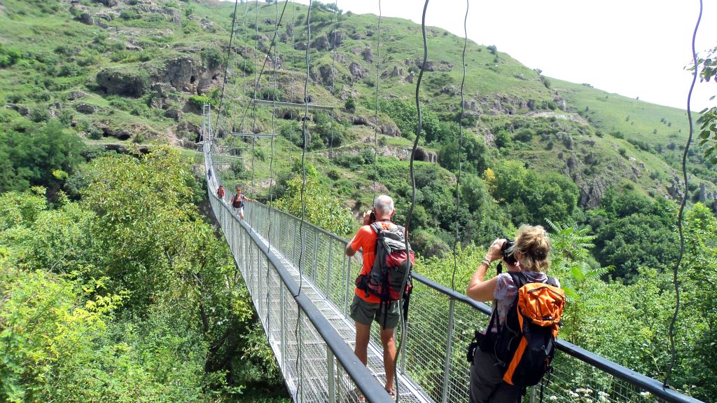 Turisti su un ponte sospeso che attraversa una valle verde, trekking di gruppo "Girolibero" in Armenia