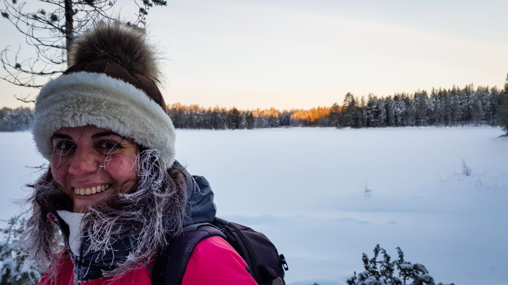 Viaggiatrice sul lago ghiacciato in Lapponia – ritratto invernale al tramonto.