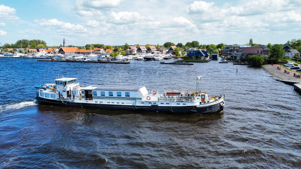 Barca fluviale "Flora" che naviga sul fiume con città tradizionale olandese sullo sfondo