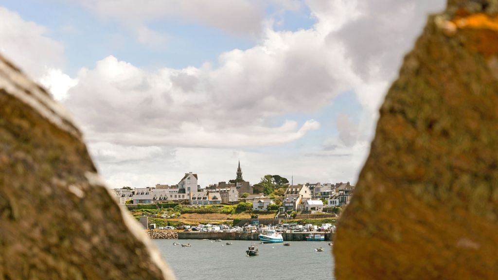 Veduta della città portuale di Le Conquet con le sue caratteristiche case in pietra, vista attraverso rocce sul lungomare