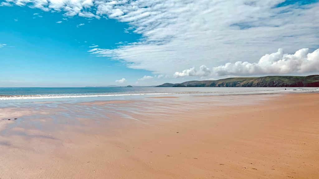 Spiaggia sabbiosa e cielo nuvoloso lungo la costa del Pembrokeshire, Galles.