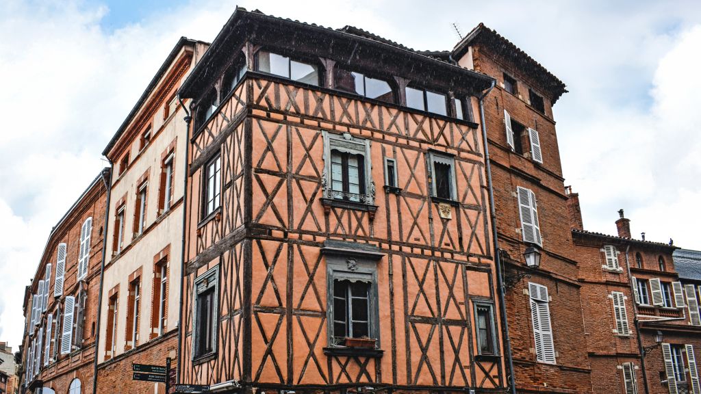 Palazzo a graticcio nel centro storico di Tolosa, Francia, con cielo sereno.