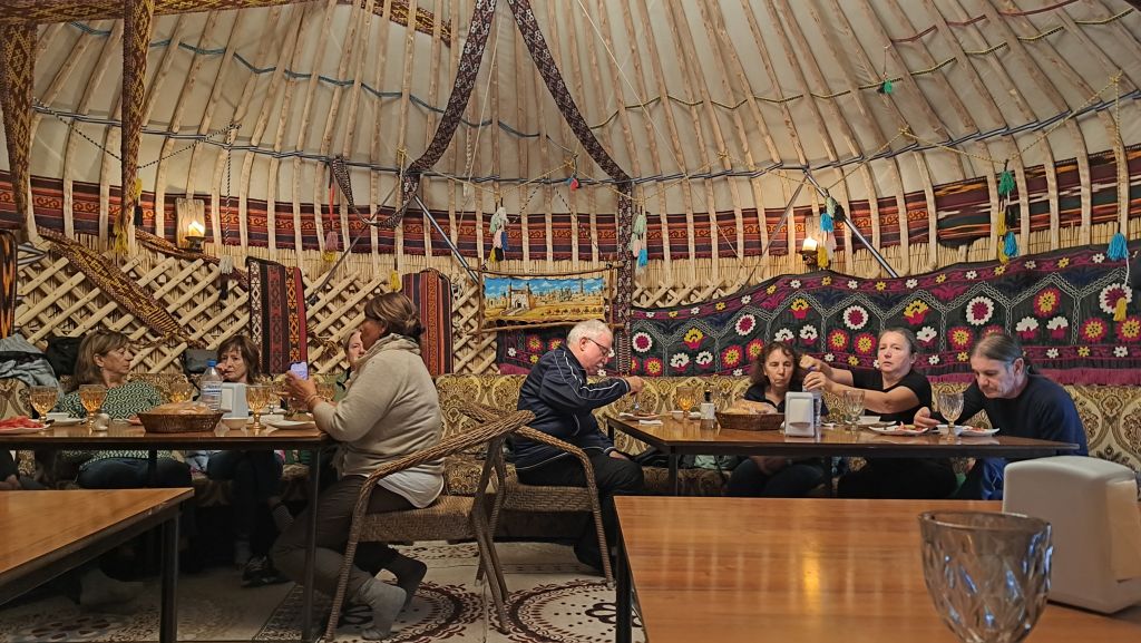 Interno decorato di una yurta uzbeka allestita per la cena con tappeti suzani, campo yurte di Nurata