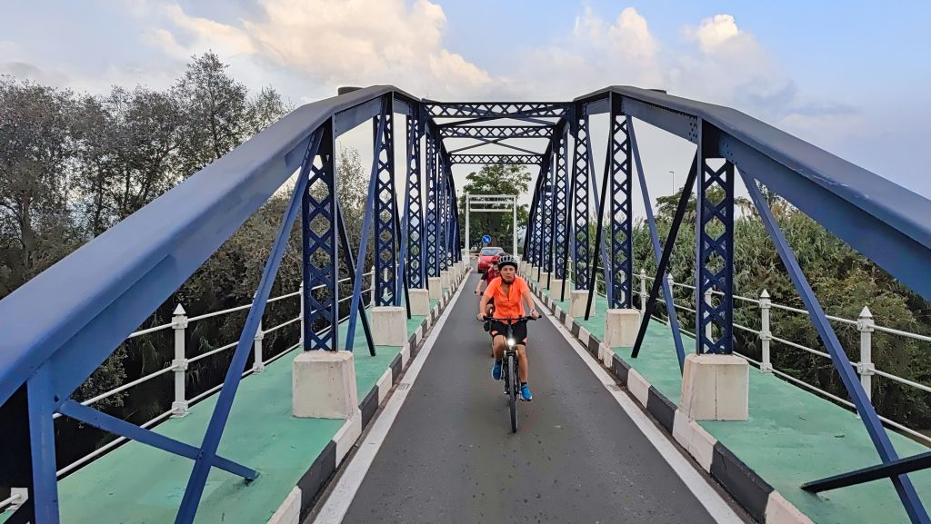 Ciclista che attraversa un ponte in ferro lungo una via verde della Spagna mediterranea.
