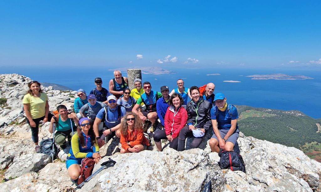 Gruppo di escursionisti in cima al Monte Attavyros, il punto più alto di Rodi, con panorama mozzafiato sull'isola durante un trekking di primavera.