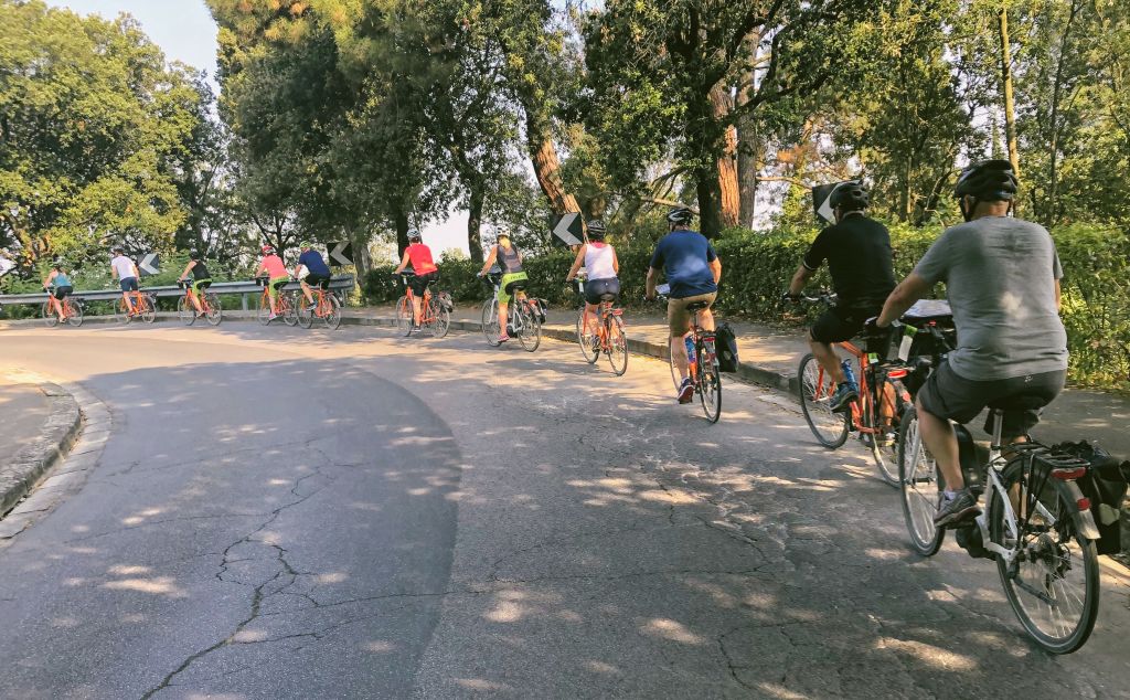 Ciclisti su una strada alberata durante un’escursione in bicicletta con Girolibero in Toscana, immersi nella natura.
