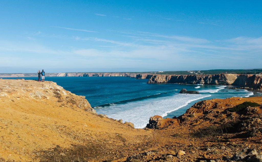Spiaggia panoramica dell'Algarve con vista sull'oceano e scogliere, turisti che guardano il panorama, trekking lungo le scogliere da Lagos a Sagres