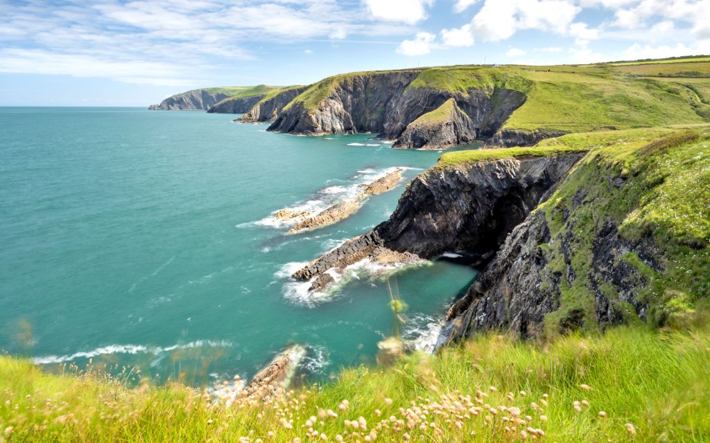 Scogliera verde e acque turchesi vicino a Ceibwr Bay, Pembrokeshire, Galles, viaggi trekking Girolibero.