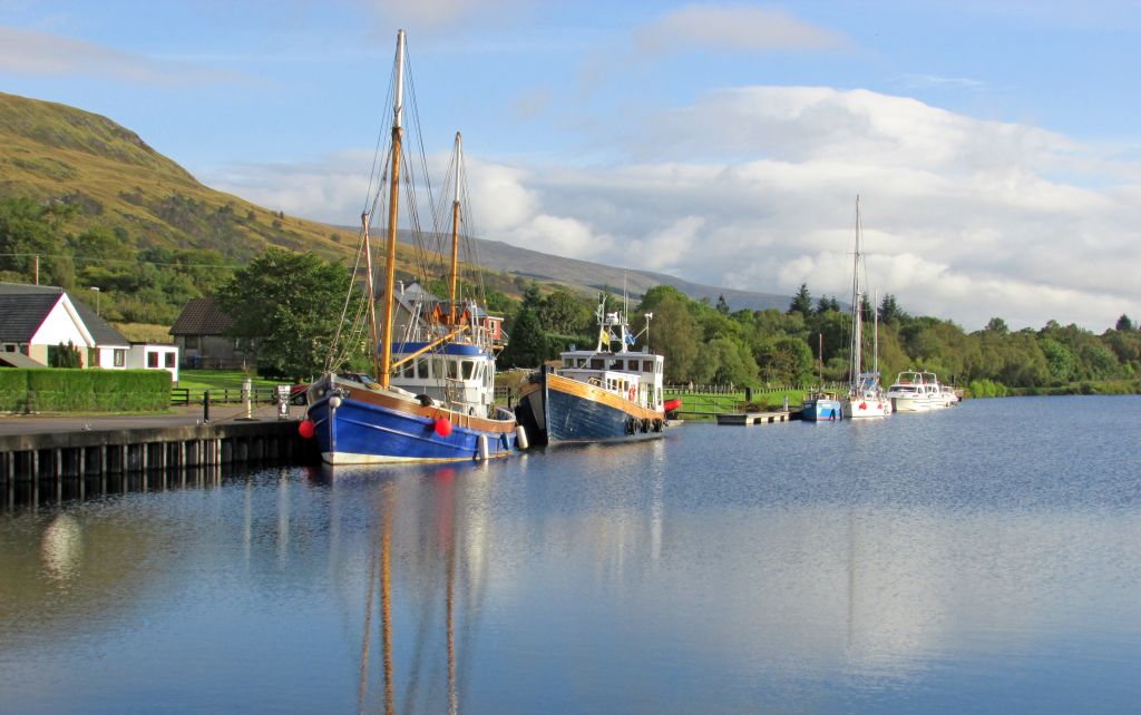 Vista panoramica del canale di Caledonia lungo il Great Glen Way, con barche a vela ancorate e montagne sullo sfondo, Scozia.