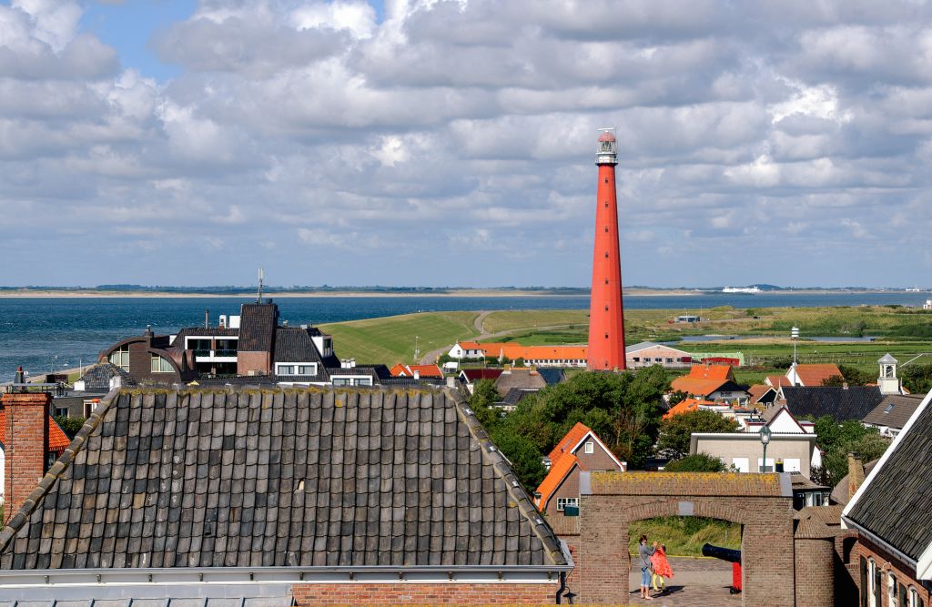 Vista panoramica del faro con tetti di case tipiche olandesi in primo piano.