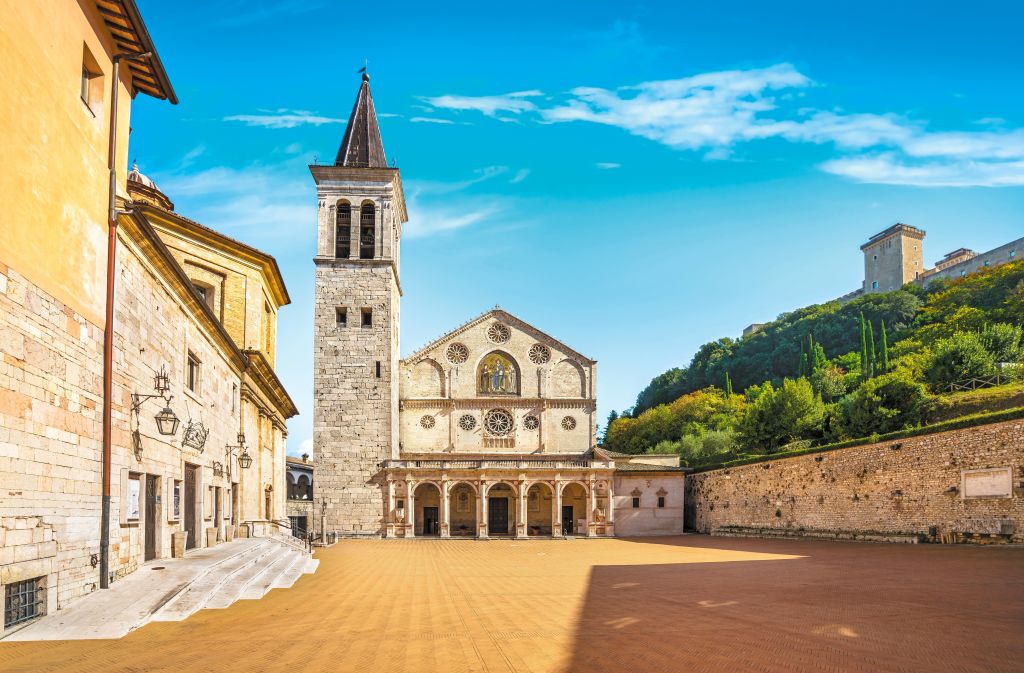 Vista della Piazza del Duomo a Spoleto con la Cattedrale di Santa Maria Assunta e il cielo blu sullo sfondo.