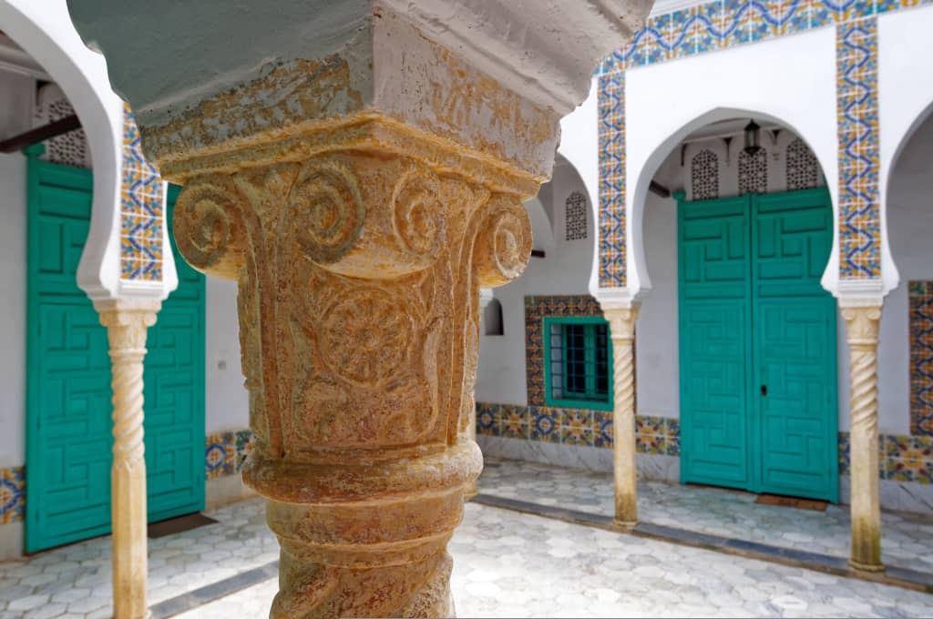 Cortile interno di un edificio storico in Algeria con colonne scolpite e decorazioni in stile islamico.