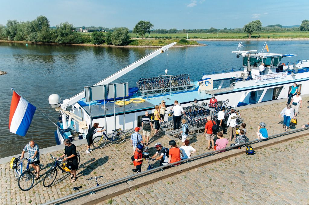 Passeggeri in attesa di imbarcarsi su una nave da crociera fluviale a un molo nei Paesi Bassi.