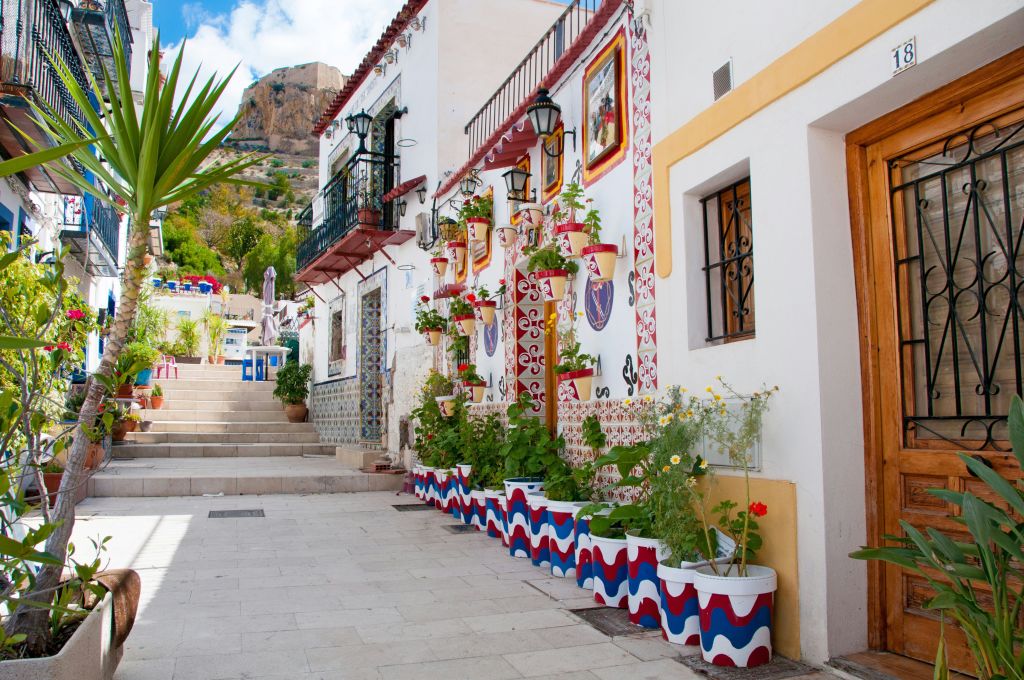 Stradina di Alicante con case bianche, fiori variopinti e atmosfera tipica di un borgo spagnolo
