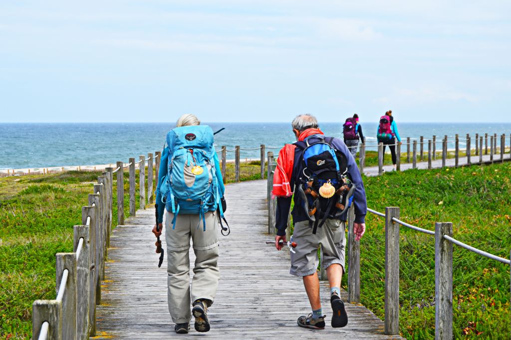 Pellegrini in cammino su una passerella verso l’oceano lungo il Cammino Portoghese.