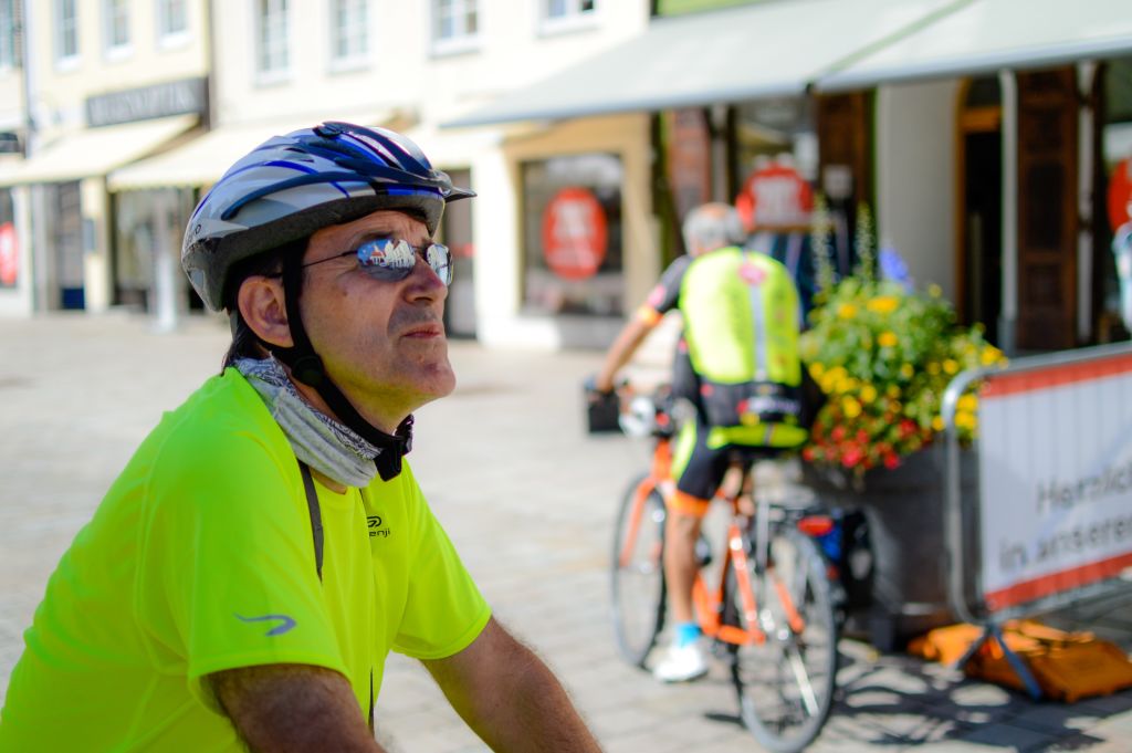 Cicloturista in pausa in un villaggio lungo la Romantische Strasse, Germania, con bici e abbigliamento sportivo.