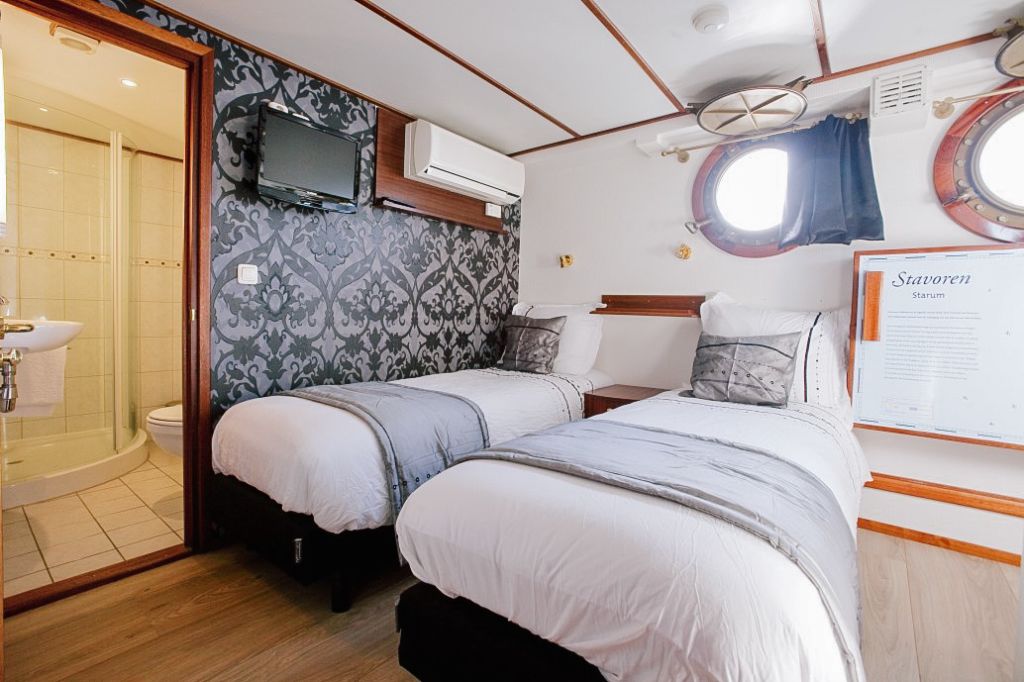 Cabina di barca di lusso con letto matrimoniale, decorazioni eleganti e oblò, viaggi confort Girolibero