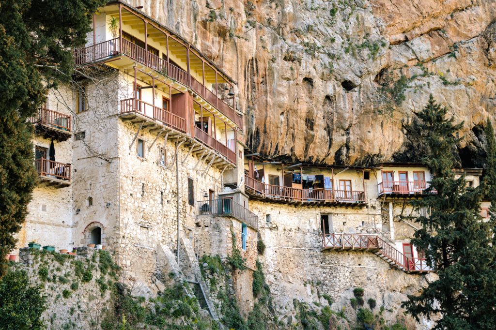 Monastero incastonato in una parete rocciosa, costruzione storica nel Peloponneso.