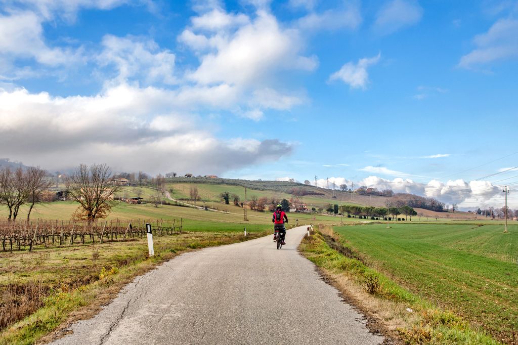 Strada panoramica tra le colline umbre, ideale per escursioni in bici con Girolibero, con paesaggi verdi e cielo limpido.