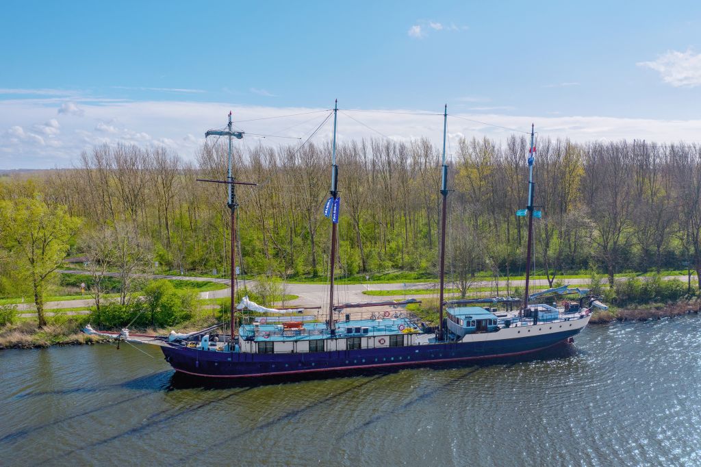 Schooner moored on a tree-lined canal in the Netherlands.